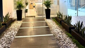 Ein Hotel Eingang mit gefliestem Weg, Blumentöpfen und einer Glasdoor.