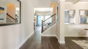 A hallway with a wooden floor, white walls, and a staircase with a glass railing. - Senoia luxury Secluded Home w/ Master on Main (Senoia)