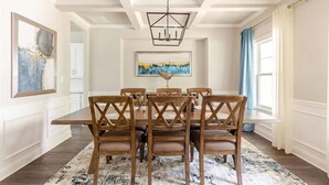 A dining room with a rectangular table, six wooden chairs with cushioned seats, a chandelier, and a large abstract painting on the wall. - Senoia luxury Secluded Home w/ Master on Main (Senoia)