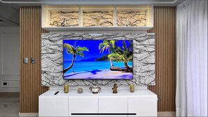 A television mounted on a marble wall with a tropical beach scene.