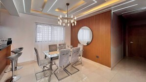 A modern dining area with a glass table, metal chairs, and a chandelier.