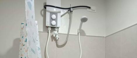 Ein Duschbereich mit Bedienfeld, einer Handbrause und einem am Wand montierten Wasserhahn.