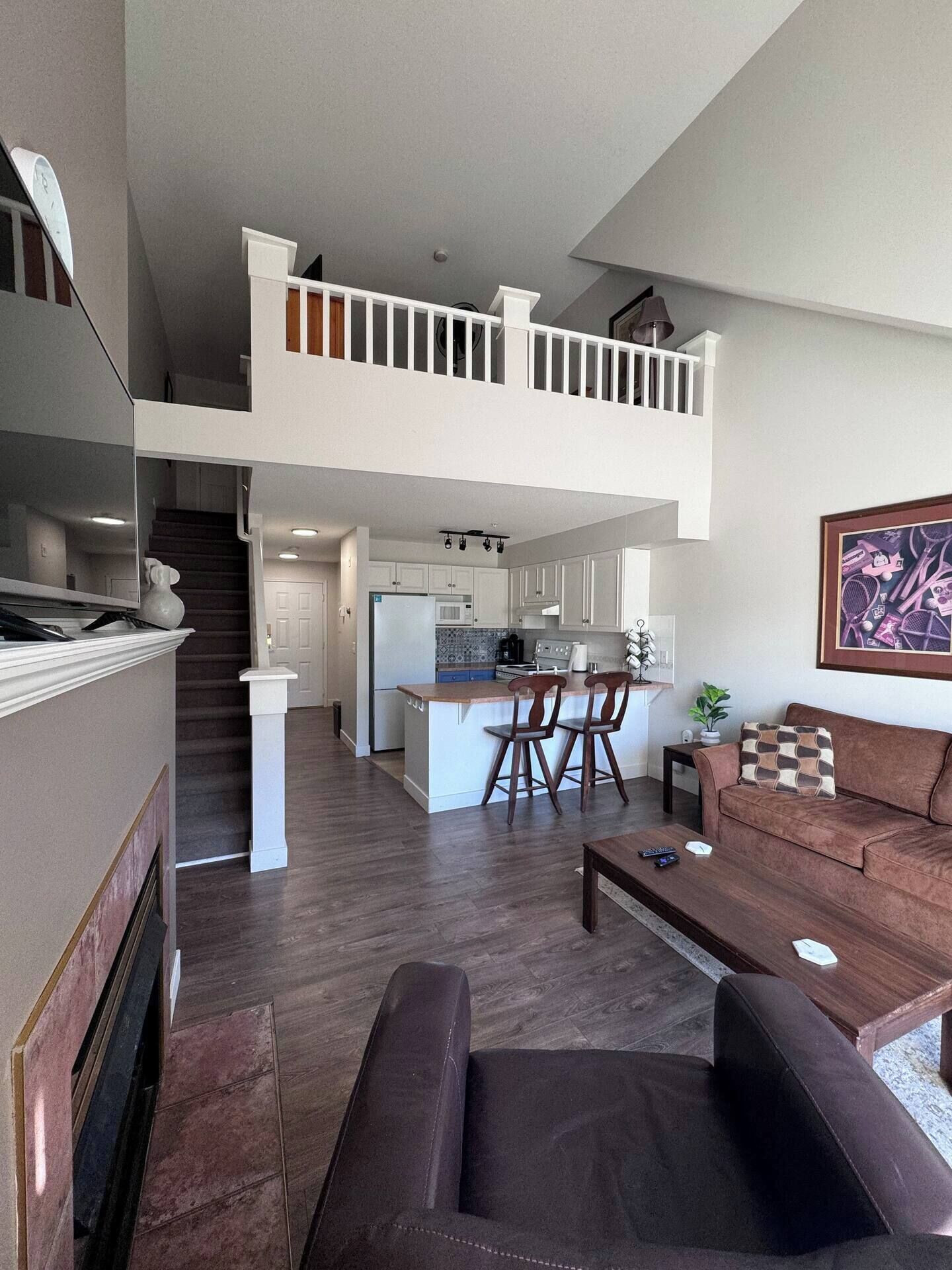 A spacious living area with a brown leather sofa, a coffee table, and a kitchen in the background.