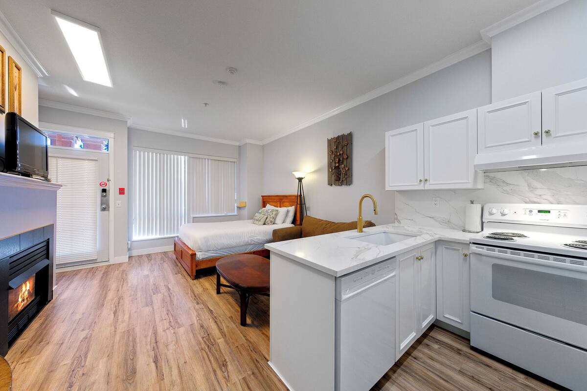 A compact kitchen with a stove, sink, and a small dining area.