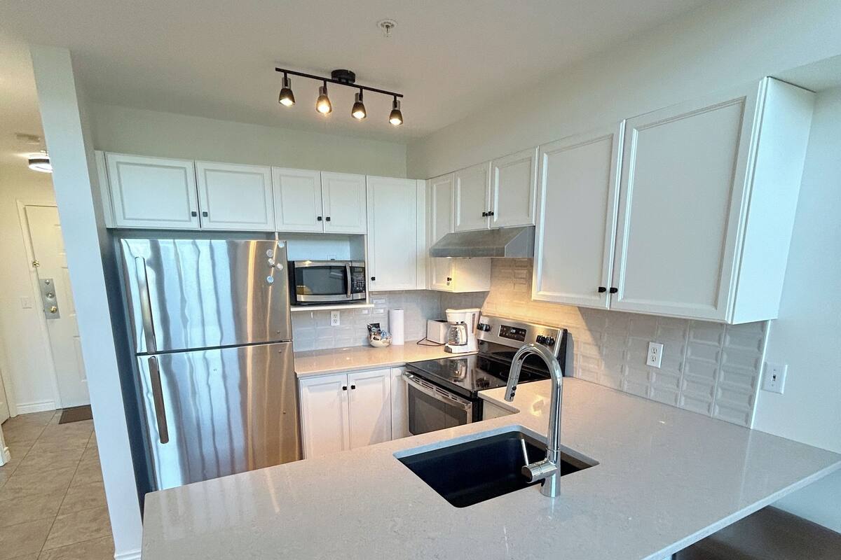 A modern kitchen with white cabinets, stainless steel appliances, and a central island with stools.