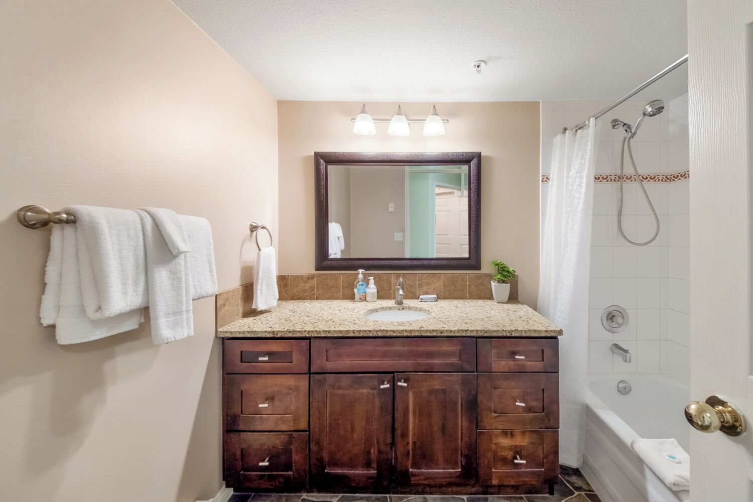 Une salle de bain équipée d’un meuble-lavabo, d’un lavabo, d’un miroir et d’une douche.
