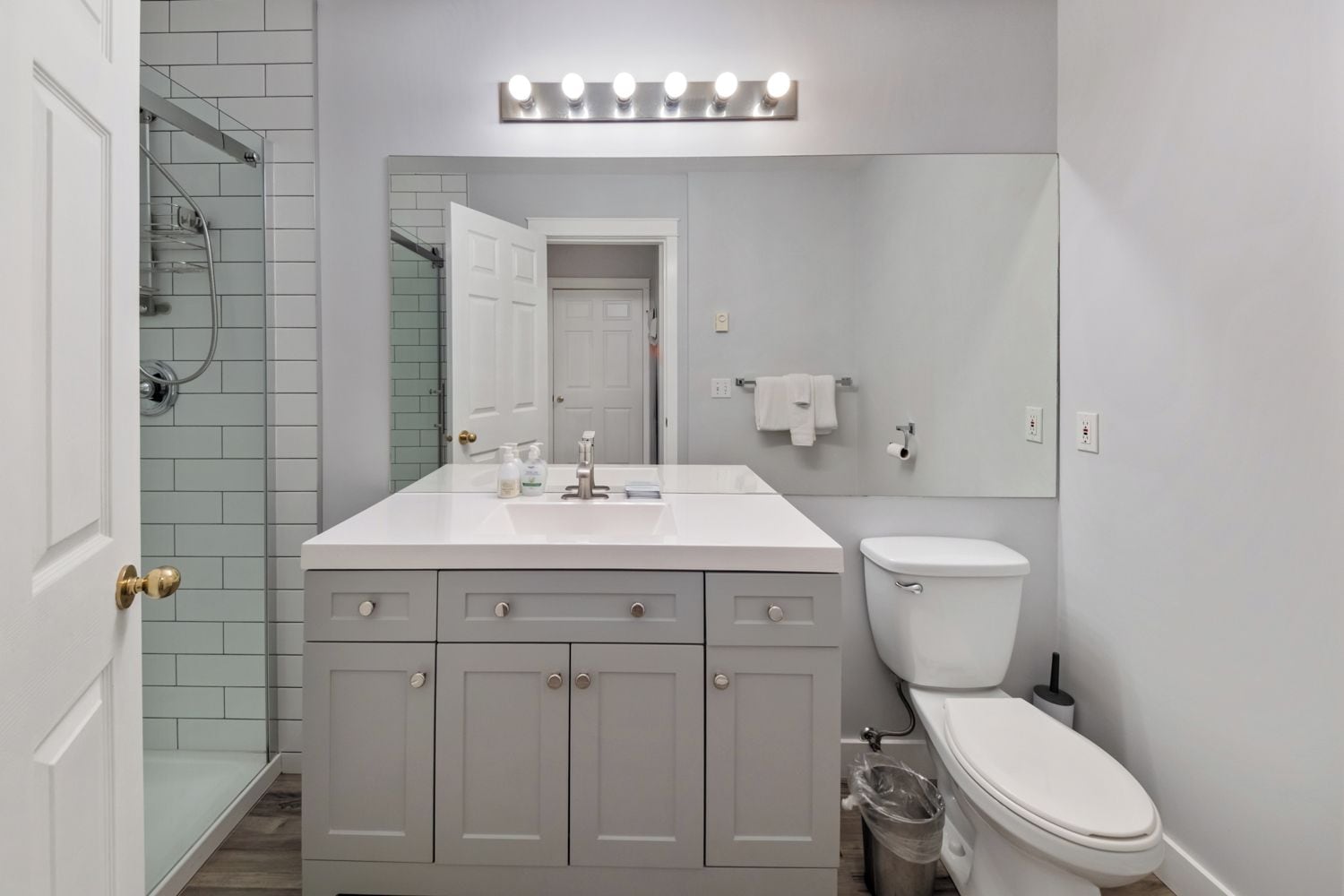 A modern bathroom with a white vanity, a toilet, and a shower area.