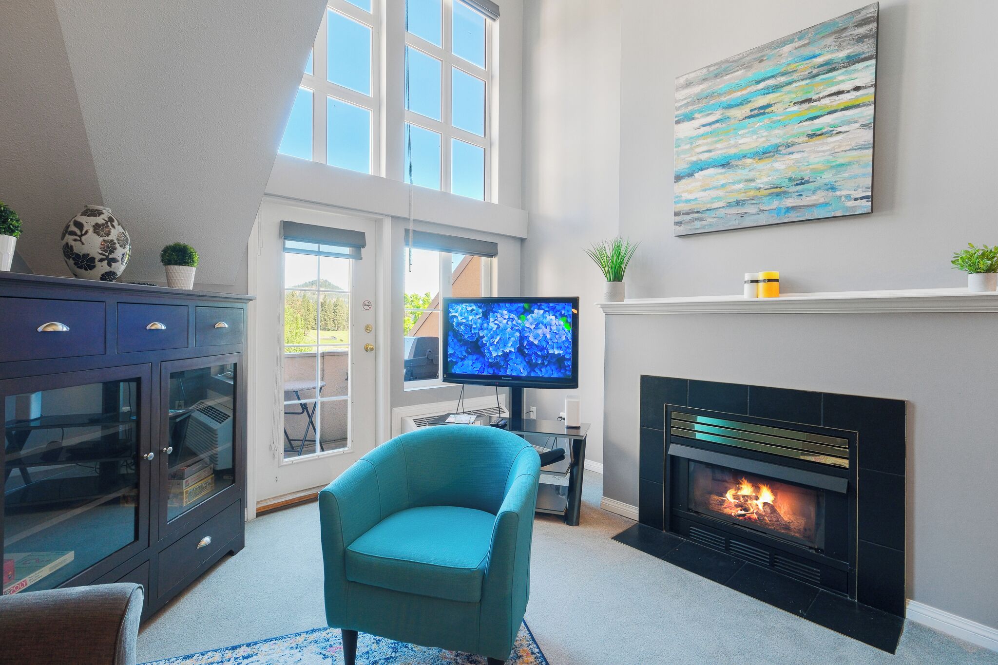Een woonkamer met een open haard, een televisie en een blauwe fauteuil.