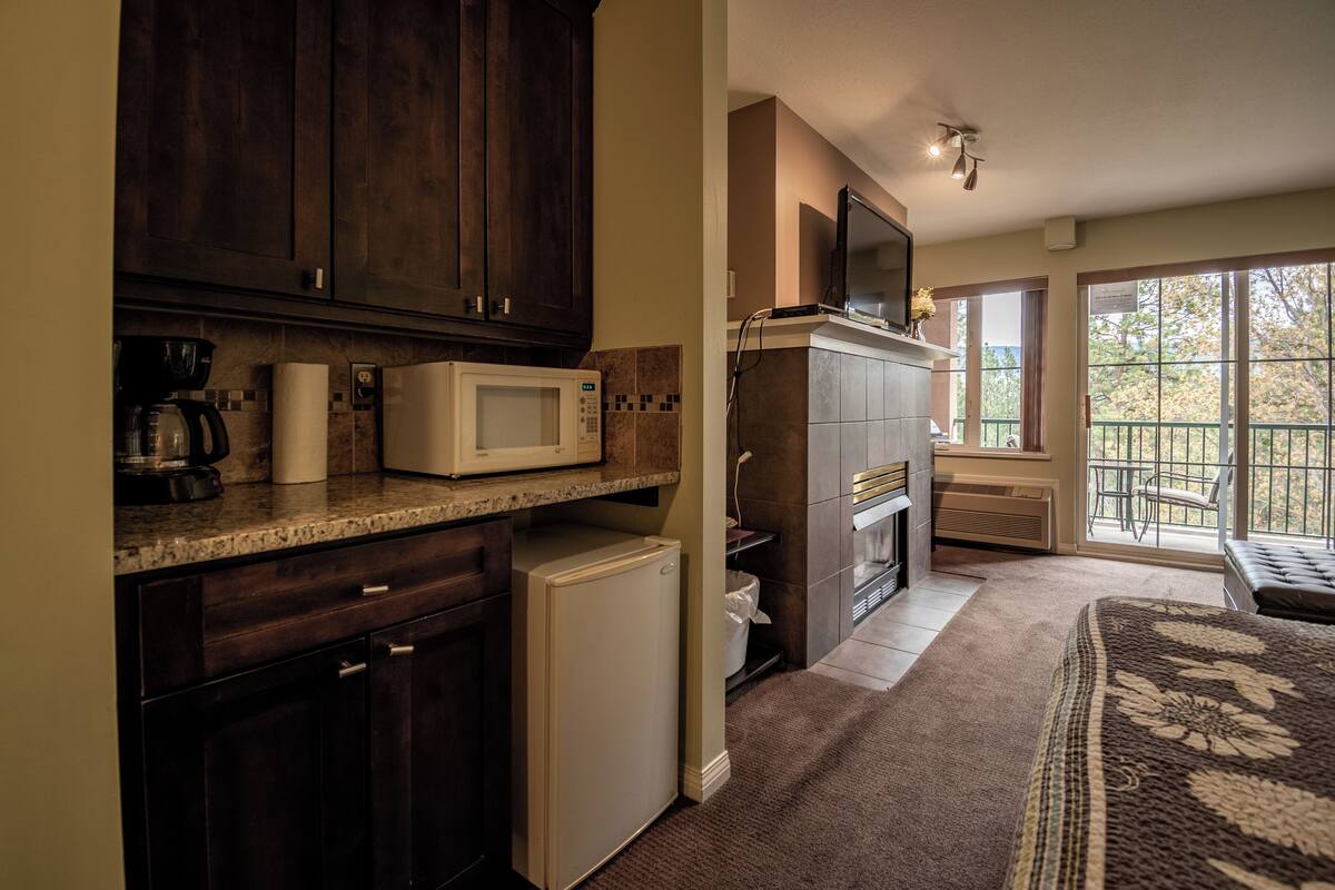 A compact kitchen with dark wood cabinets, a microwave, and a small refrigerator.
