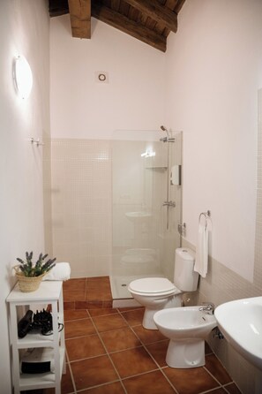 Un baño con ducha, inodoro, bidé y lavamanos.