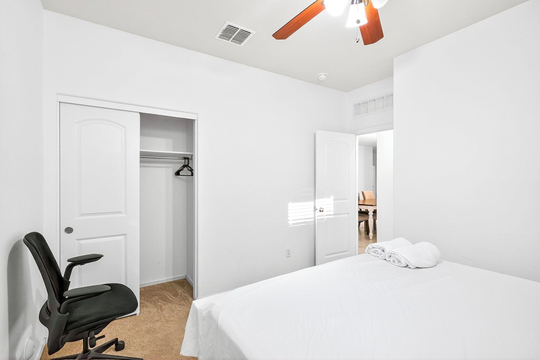 A hotel room with a bed, a chair, a wardrobe, and a mirror.