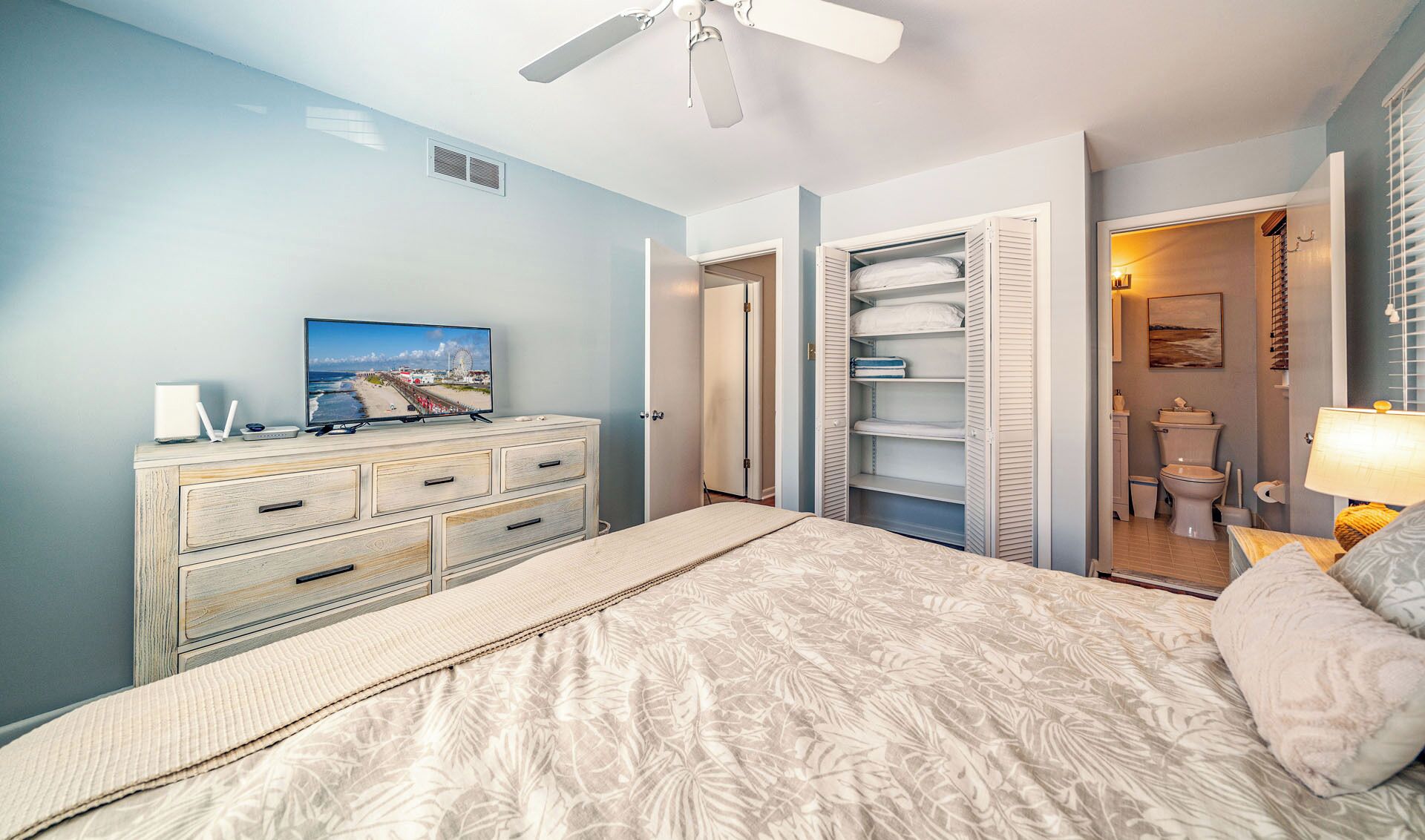 Quarto com cama, cômoda, televisão e armário.