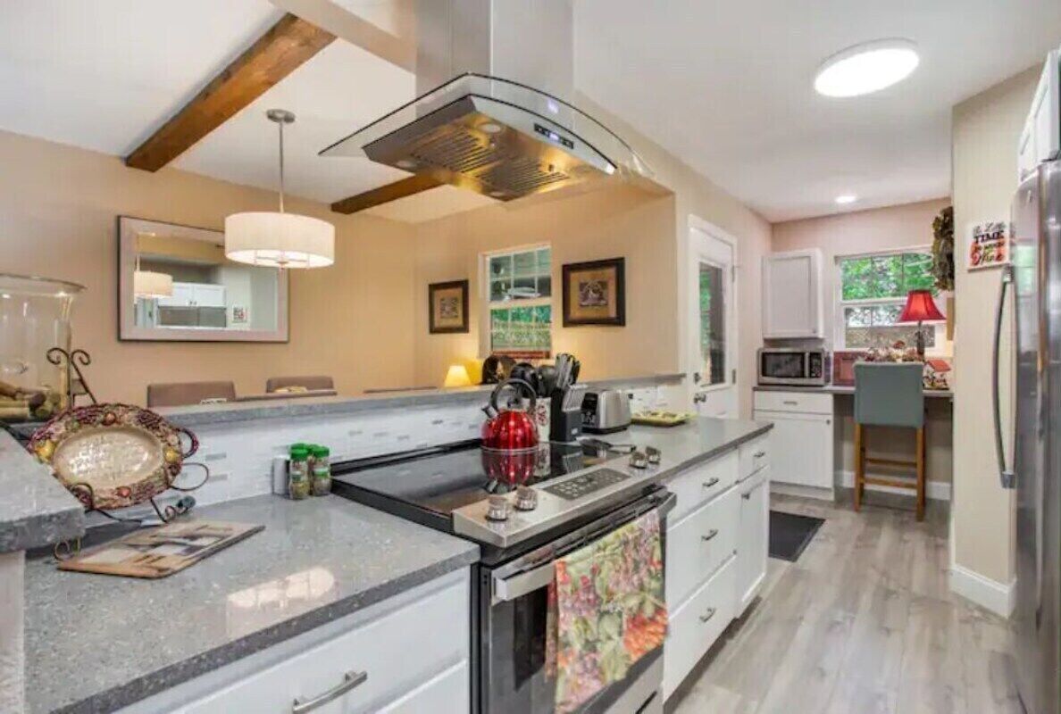 A modern kitchen with a central island, stainless steel appliances, and a pendant light.