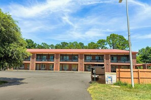A two-story brick building with a red roof, large windows, and a fenced parking area. - Sunrise Inn By OYO Albany (Albany)