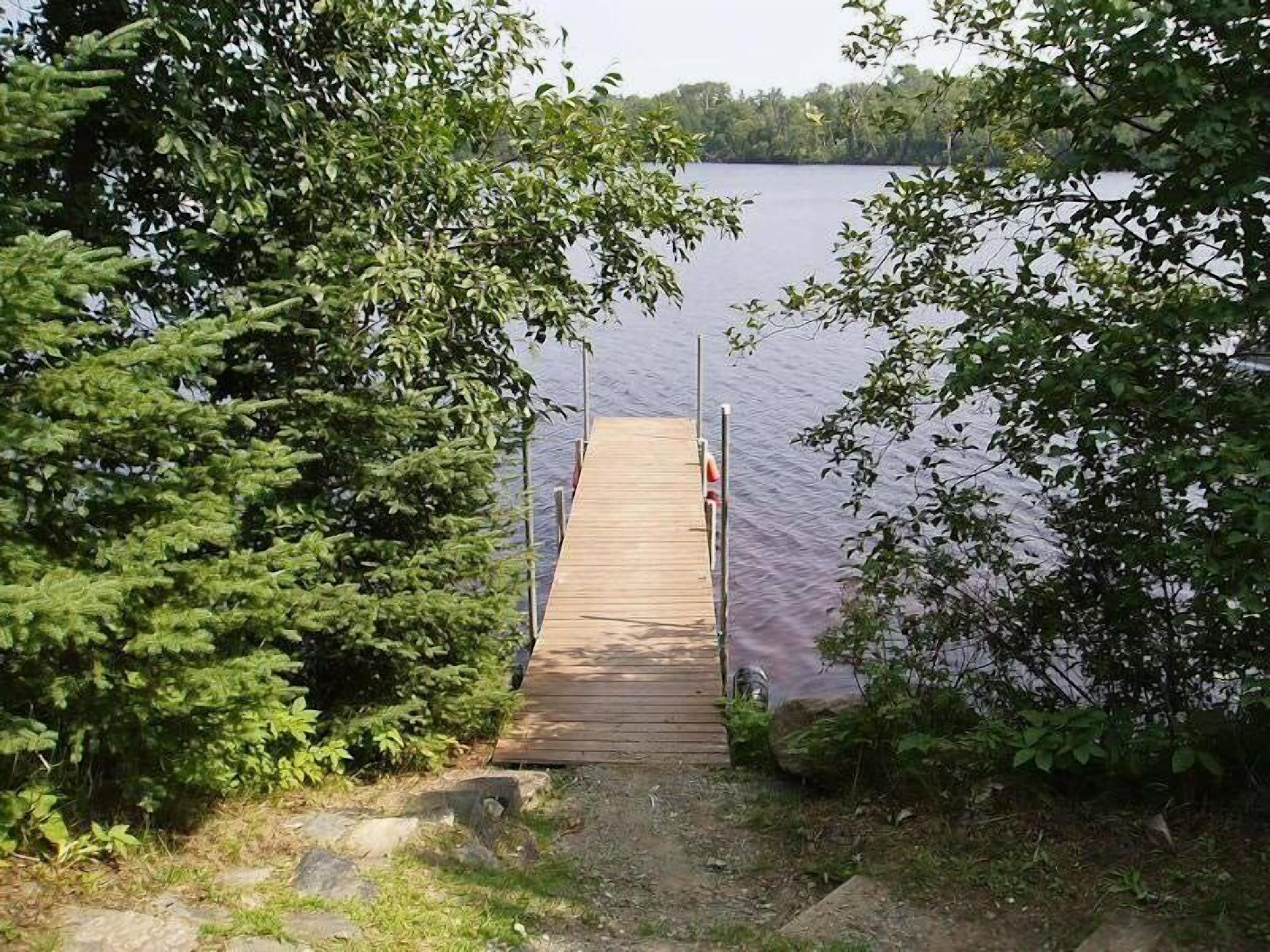 Une jetée en bois mène à un lac paisible, entouré d’une végétation luxuriante.