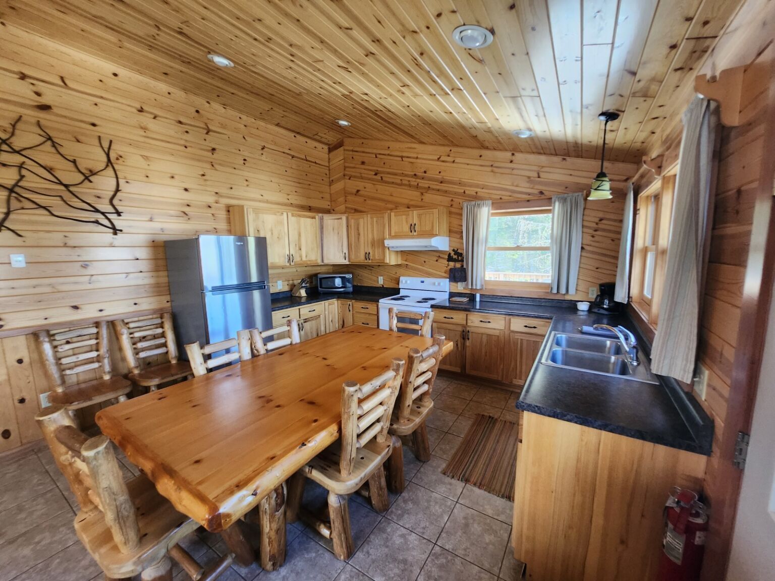 A wooden cabin interior with a kitchen, dining table, and chairs.