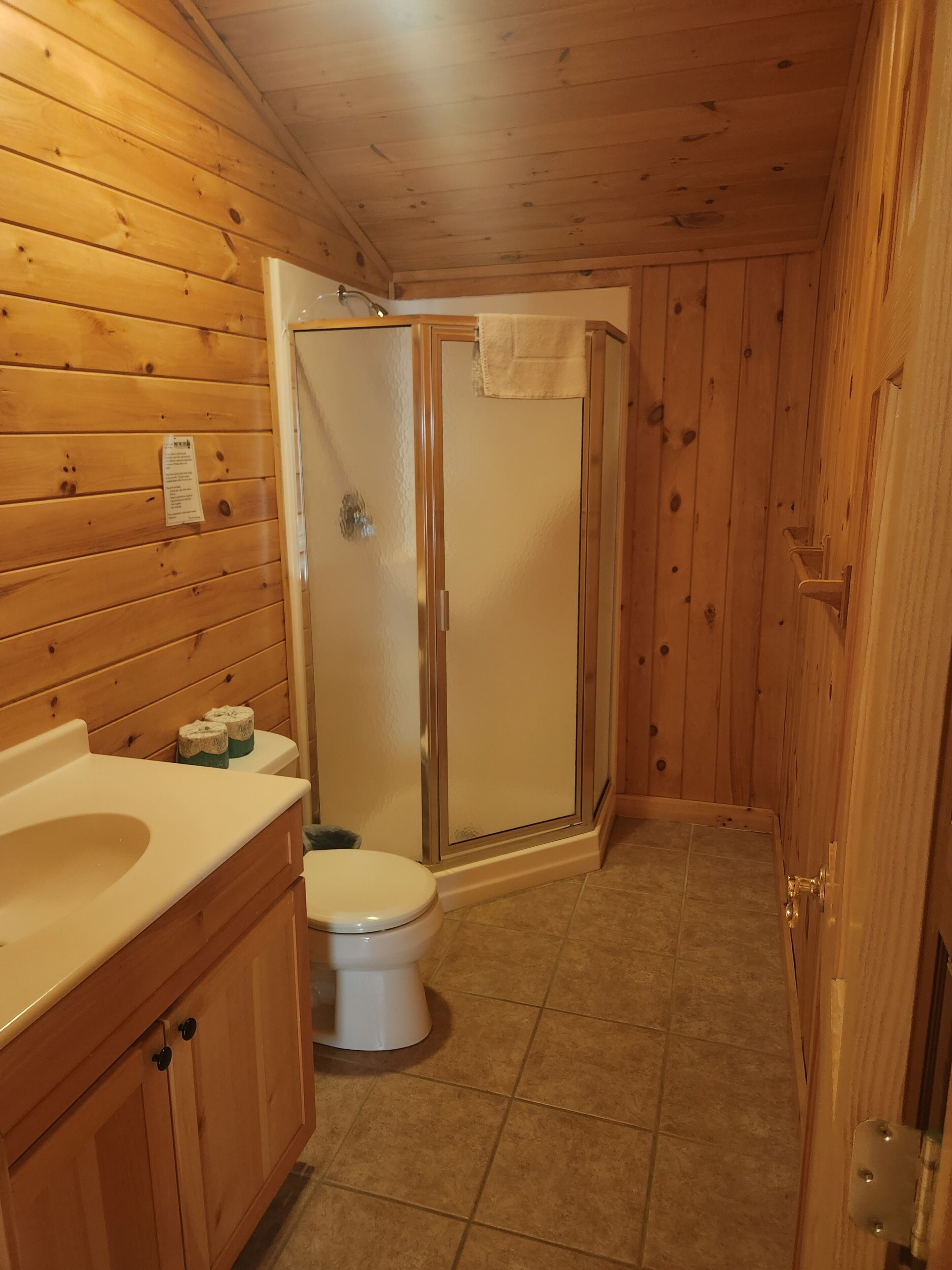 Ein Badezimmer mit Holzwandverkleidung, Toilette, Waschbecken und Dusche.