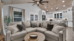 A modern living room with a sectional sofa, a round coffee table, and a ceiling fan. - Cozy Country Cabin in the Woods (Dayton)