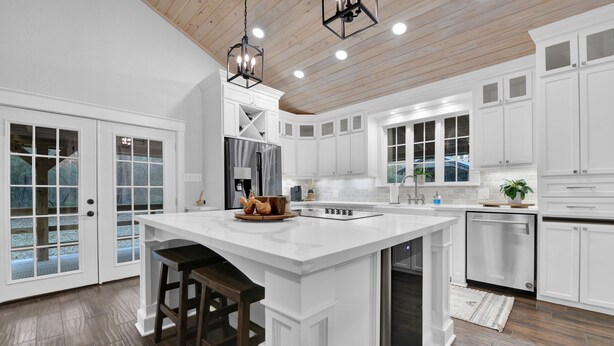 A spacious kitchen with white cabinetry, a large island, and a wooden ceiling. - Cozy Country Cabin in the Woods (Dayton)