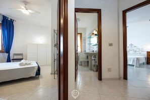 Une chambre d’hôtel avec un lit, un bureau, une chaise, une armoire et une salle de bain visible à travers une porte ouverte.
