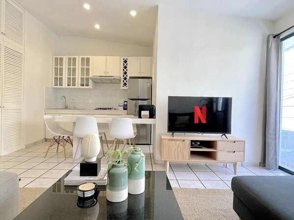 A modern living room with a flat-screen TV, a coffee table, and a sofa.