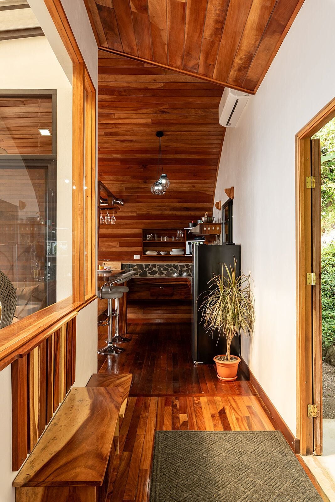 Una cocina moderna con armarios de madera, un refrigerador negro y una lámpara colgante.