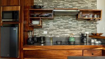 A modern kitchen with wooden cabinetry, a built-in microwave, a gas stove, a blender, a kettle, and various kitchen utensils.