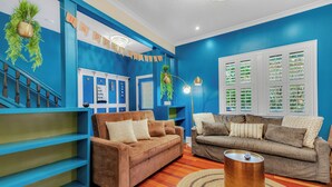 A living room with two sofas, a coffee table, and a staircase with blue walls and white railings. - 1142- Bamboo Oasis, Great Entertaining, 1 Mile to Arenas, Pet & Family Friendly (Jacksonville)