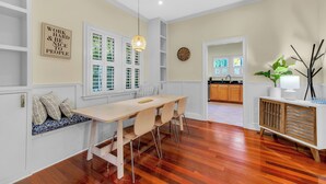 A dining area with a wooden table and chairs, a bench with cushions, a pendant light, and a wall-mounted clock. - 1142- Bamboo Oasis, Great Entertaining, 1 Mile to Arenas, Pet & Family Friendly (Jacksonville)