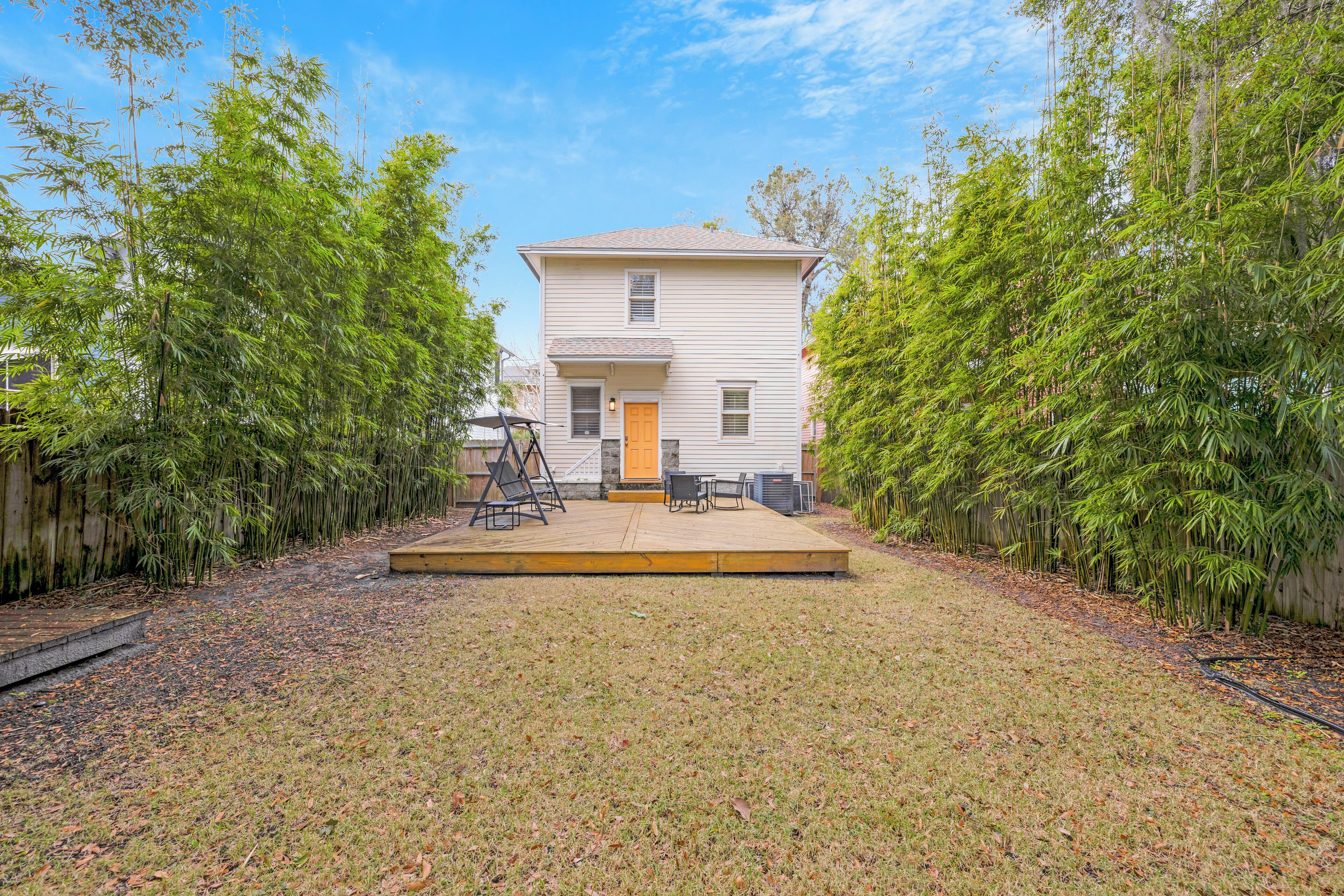 A two-story house with a front porch, a swing set, and a small patio area.