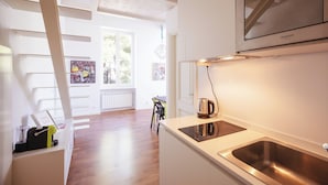 A modern kitchen with a built-in stove, a stainless steel sink, and a wall-mounted television. - Belvedere Hambury Apartment by Wonderful Italy (Bordighera)