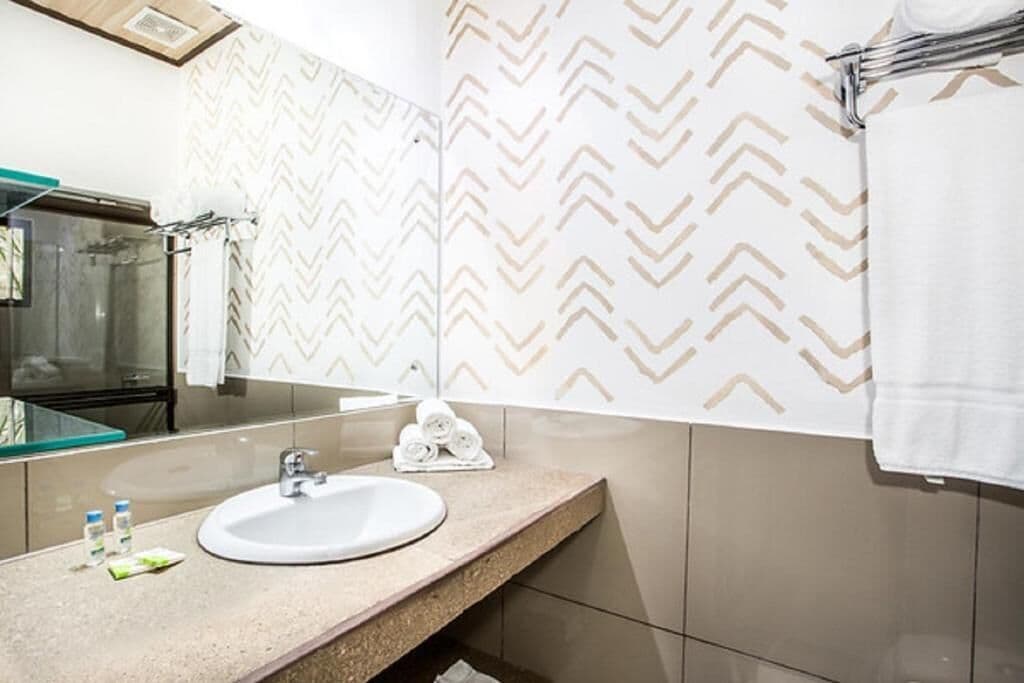 Un baño con lavamanos blanco, cabina de ducha con paredes de vidrio y espejo.