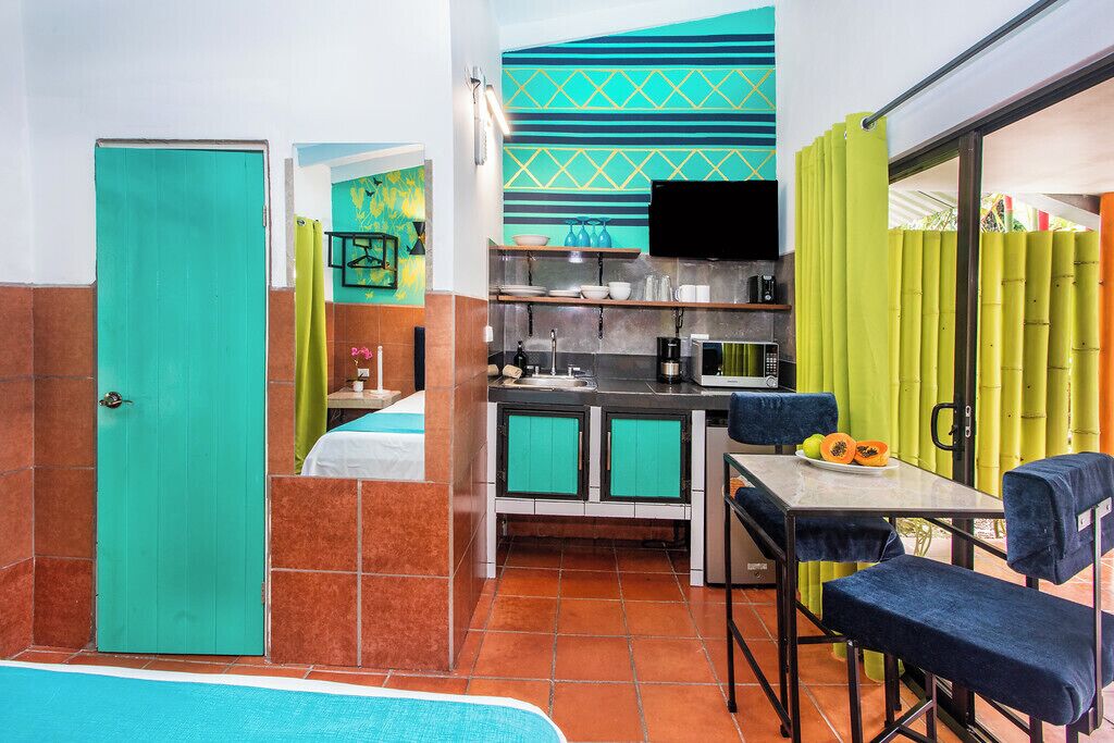 A compact hotel room with a kitchenette, a dining area, and a bathroom.