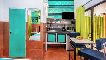 A compact hotel room with a kitchenette, a dining area, and a bathroom.