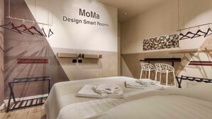 A modern hotel room with a bed, a wall-mounted towel rack, a coat rack, and a sign reading "MoMa Design Smart Rooms". - Moma - Design Smart Rooms - Bari Central Station (Bari)