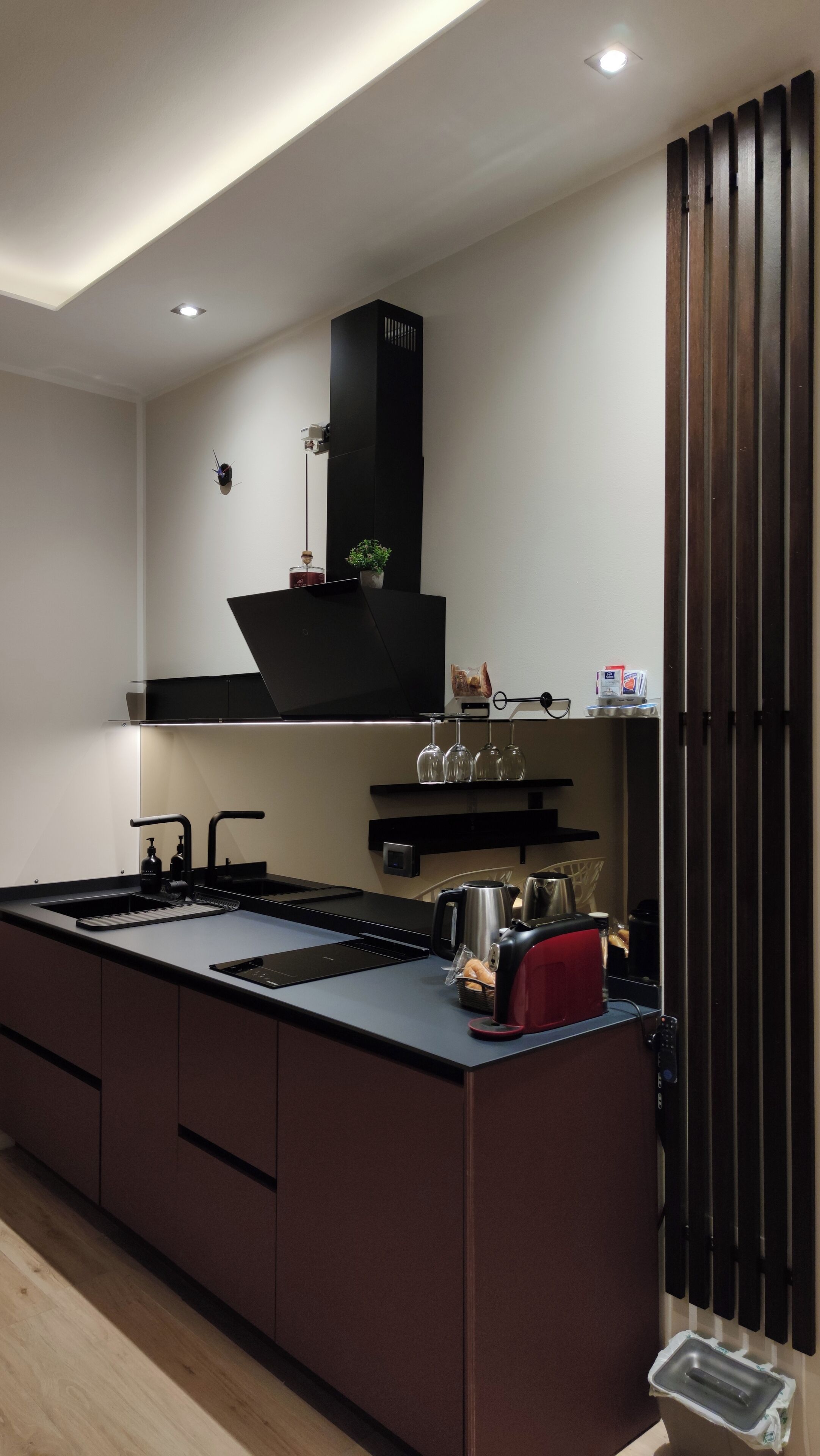 A modern kitchen with a central island, built-in appliances, and a sleek black backsplash.