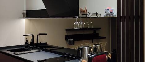 A modern kitchen with a central island, built-in appliances, and a sleek black backsplash.
