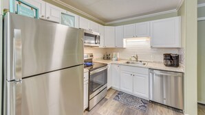 Una cocina con gabinetes blancos, electrodomésticos de acero inoxidable y salpicadero.
