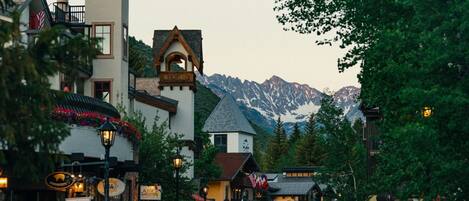 A street with buildings, a mountain in the background, and a sign for 'Alpine Gardens.'