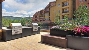 An outdoor patio with a barbecue grill, seating area, and flower planters. - Premier Ski Condo w/ Slopeside Access (Breckenridge)