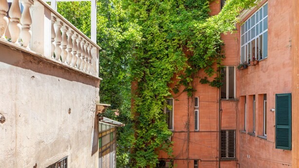 A narrow alleyway between buildings with a white balustrade and a building with green shutters. - iFlat | Soft & Relaxing apt in Trastevere (Roma)