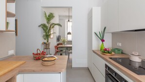 A modern kitchen with a wooden countertop, a dining area with chairs, and a potted plant. - iFlat | Soft & Relaxing apt in Trastevere (Roma)