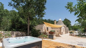 A hot tub on a wooden deck with a stone building in the background. - Trullo Fragno by Wonderful Italy (Noci)