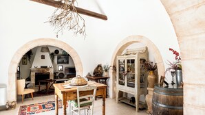 A rustic interior with stone arches, a wooden table, and a cabinet with glass doors. - Trullo Fragno by Wonderful Italy (Noci)