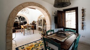 A dining area with a wooden table, green chairs, and a woven pendant light. - Trullo Fragno by Wonderful Italy (Noci)