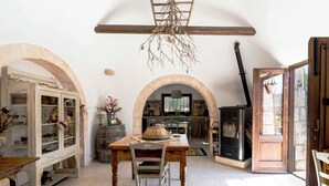 A rustic kitchen with an open archway, wooden furniture, and a wood-burning stove. - Trullo Fragno by Wonderful Italy (Noci)