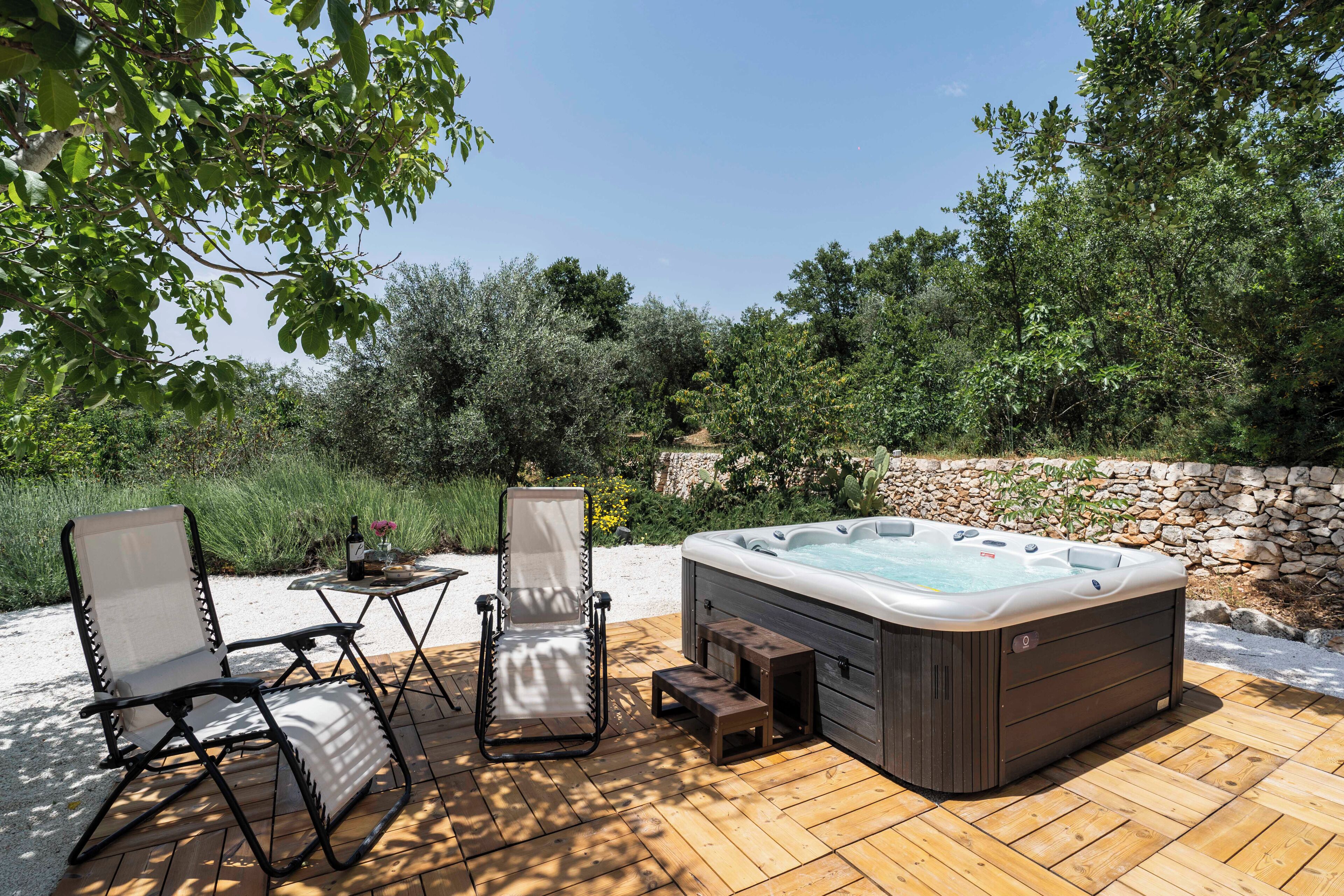 Un jacuzzi en una terraza de madera con dos sillas y una mesita.