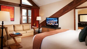 A hotel room with a bed, a sofa, a television, and a desk with a lamp. - Deluxe King Room at Stunning Complex with Sauna (Beaver Creek)