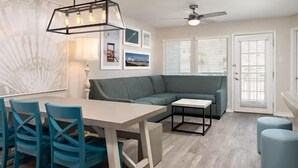 Un salon moderne comprenant un coin repas, un ventilateur de plafond et une grande fenêtre équipée de stores.