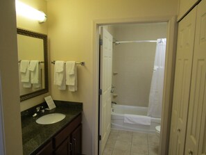 A bathroom with a sink, mirror, and a shower area. - Queen Suite with In-Suite Conference Space Near the University of Rochester (Rochester)